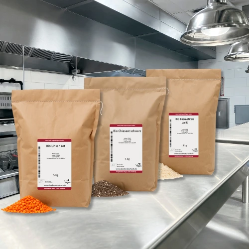 Three paper bags on a stainless steel table in a professional kitchen