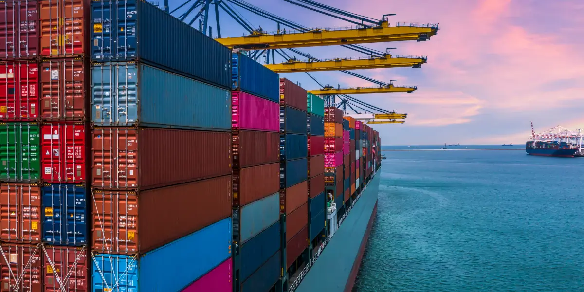 Loaded container ship at the terminal, pink sky and blue-green water