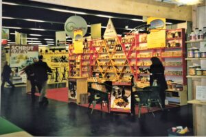 Messestand aus Holz mit vielen kleinen F&auml;chern, Tresen, Tisch und St&uuml;hlen