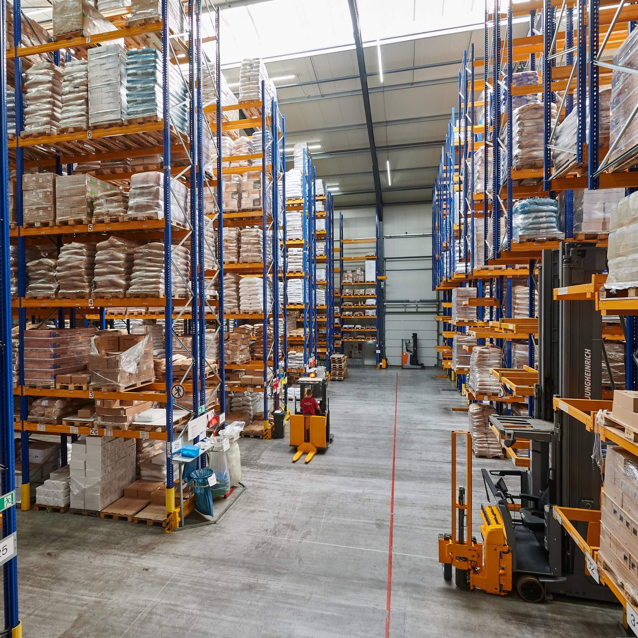 View into the high-bay warehouse, a forklift is driving through the wide aisle