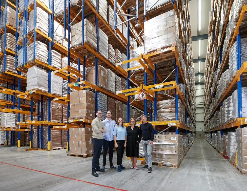 The Bode family in the large warehouse with filled pallet racks in the background.
