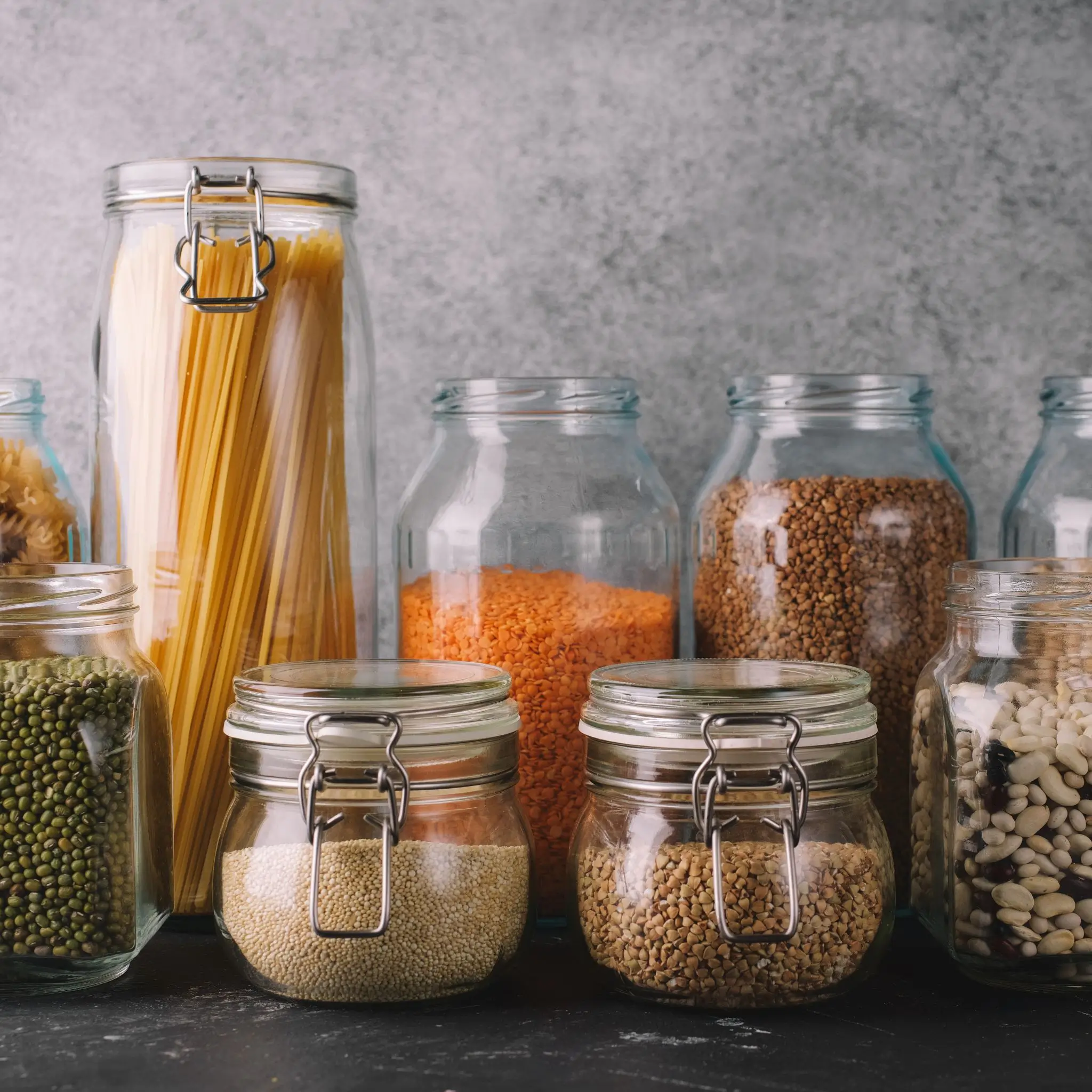 Storage jars with pasta, legumes, and grains are lined up behind one another