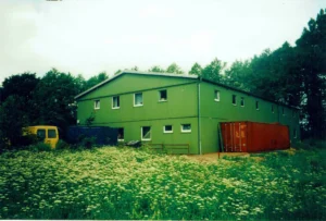 Gr&uuml;ne Lagerhalle umgeben von wilder, bl&uuml;hender Wiese