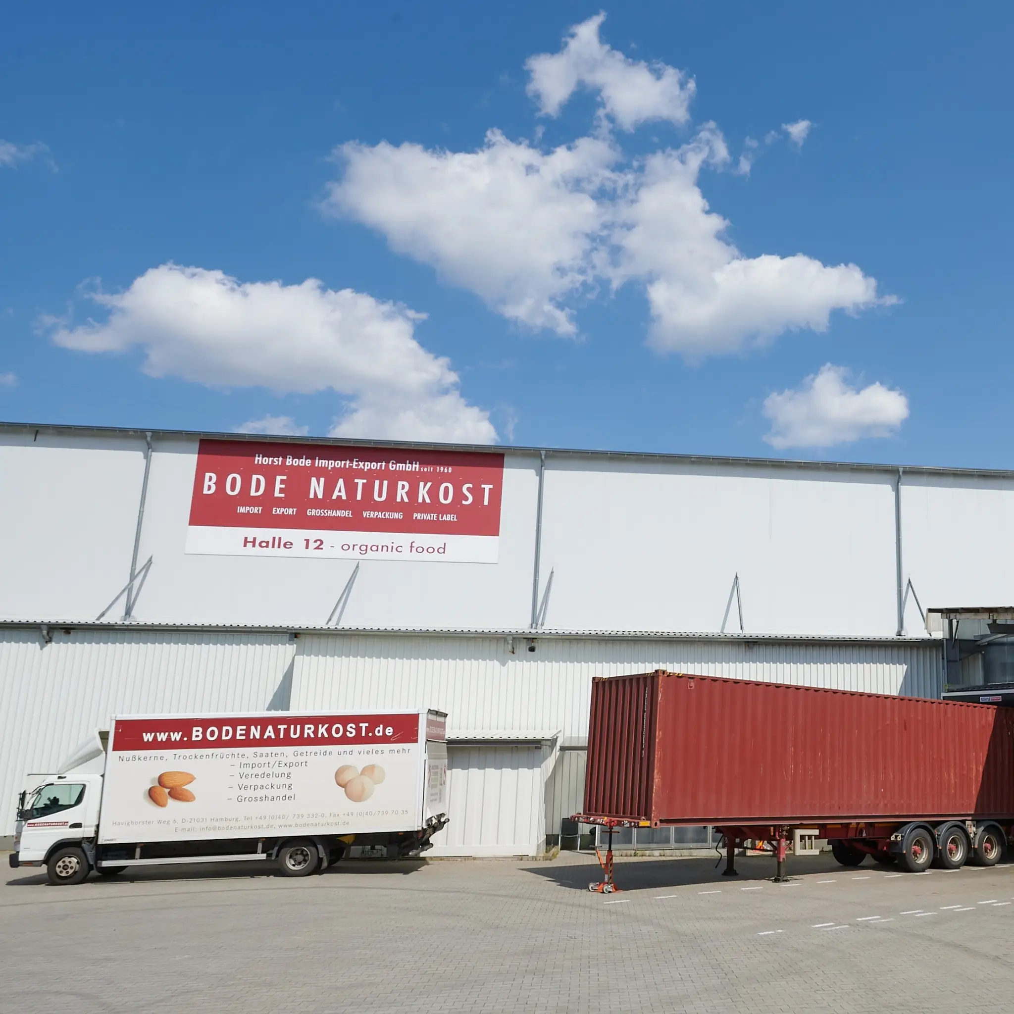 Exterior view of the warehouse with a large Bode Naturkost sign, with a Bode truck and a container for unloading in front