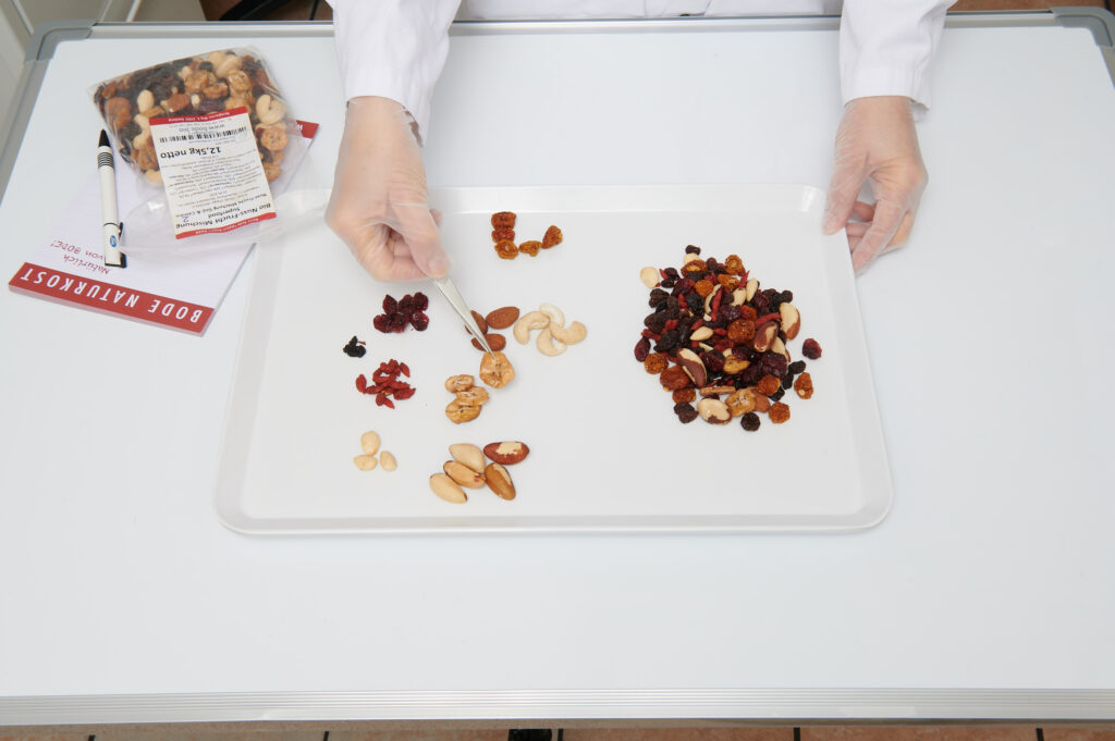Quality control of trail mix in the laboratory, looking at a tray where a person is sorting the ingredients with tweezers.