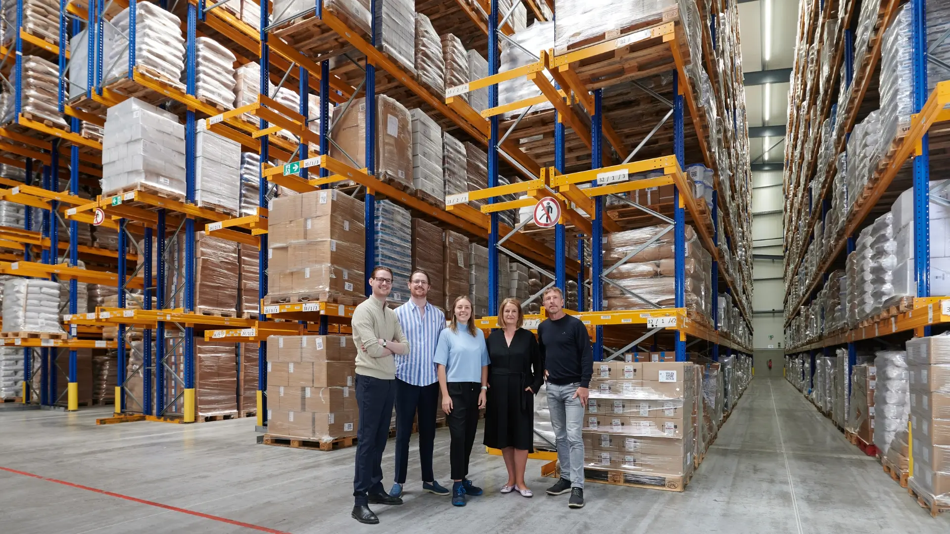 The Bode family in the large warehouse with filled pallet racks in the background.
